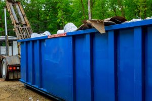 Blue dumpster with what looks like cardboard and other waste